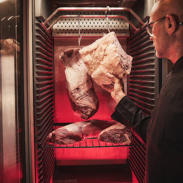 Rainer Trautenbach inspiziert Fleisch im Dry Ager Reifeschrank mit blauer Beleuchtung