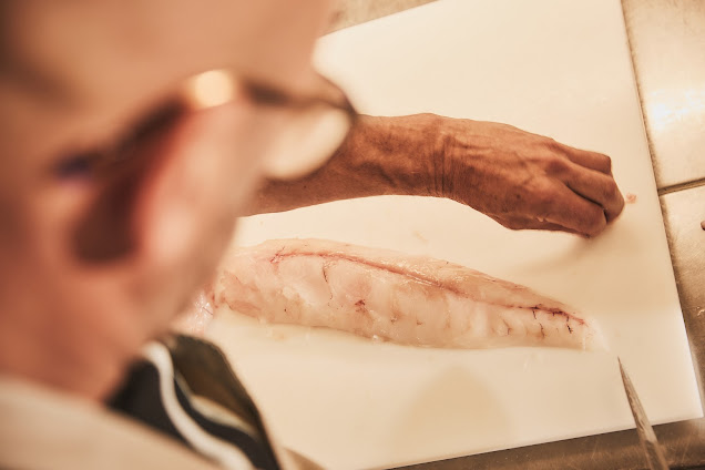 Rainer Trautenbach untersucht weißes Heilbutt-Filet auf einem Schneidebrett