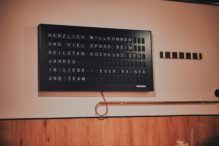 Flipboard-Tafel im Weinforum mit Text: Herzlich Willkommen und Viel Spaß beim geilsten Kochkurs des Jahres – In Liebe, Euer Rainer und Team