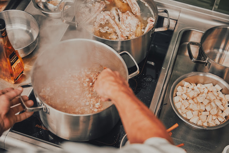 Köche rühren in dampfenden Töpfen auf dem Herd – Sous-Vide und Schmoren im Kochkurs