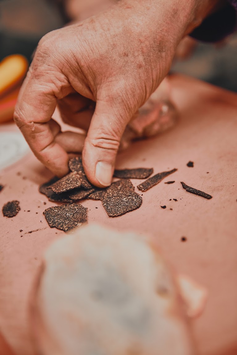 Nahaufnahme: Hände legen Trüffelscheiben unter die Haut eines Geflügels