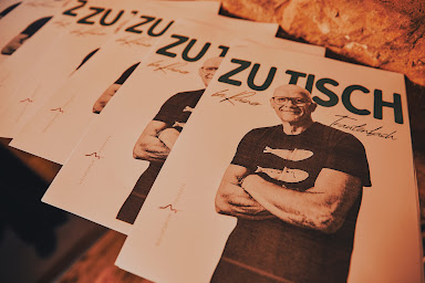 Mehrere Exemplare des Kochbuchs 'Zu Tisch bei Rainer Trautenbach' auf einem Tisch