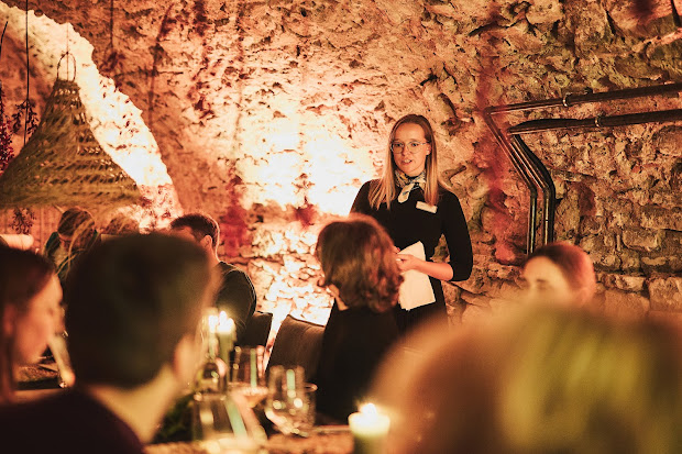 Serviceteam bedient Gäste am Tisch im Kerzenlicht des historischen Gewölbekellers