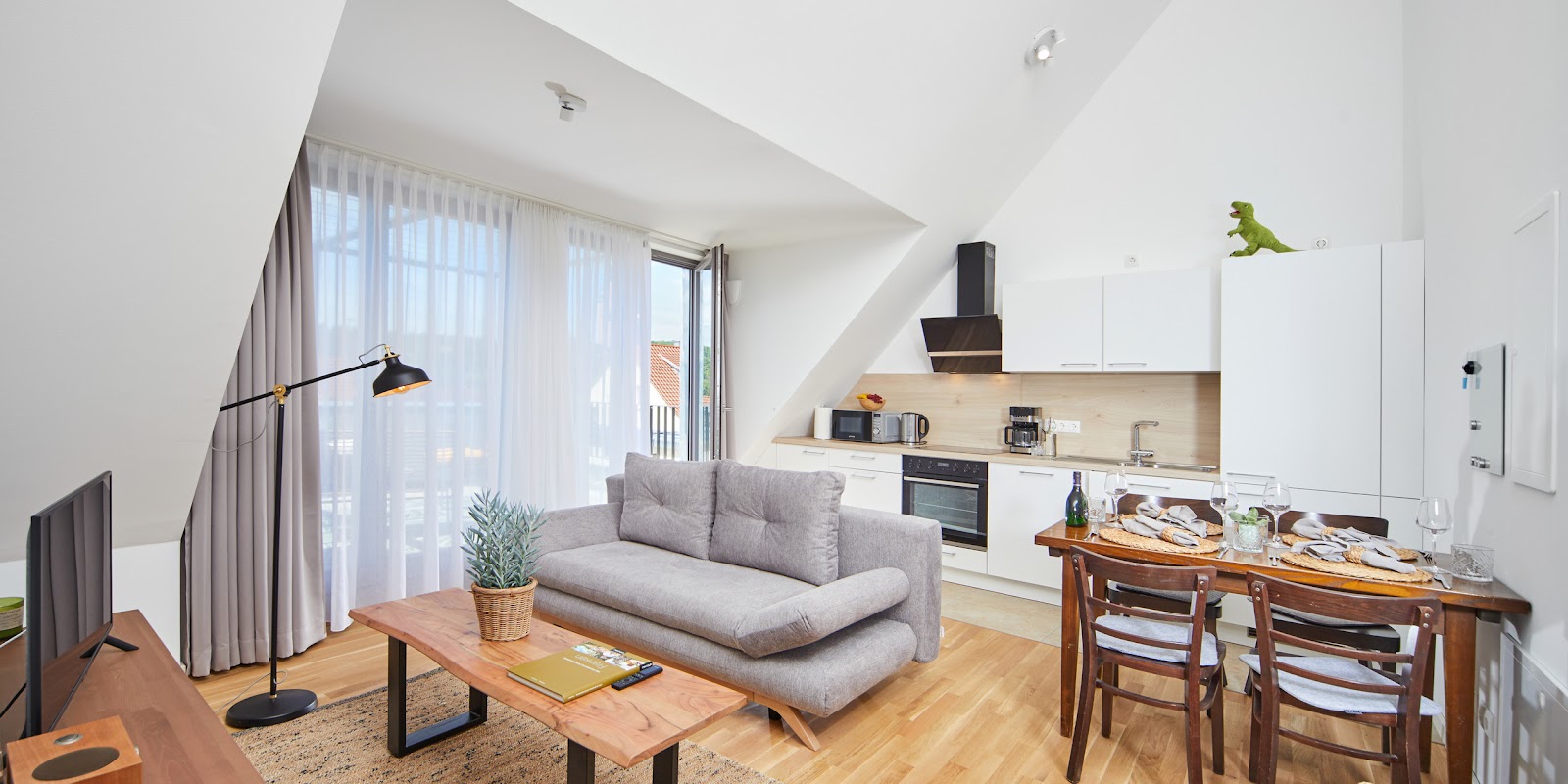 Offener Wohn- und Küchenbereich der Ferienwohnung Weinforum Franken Eibelstadt mit Sofa und gedecktem Esstisch