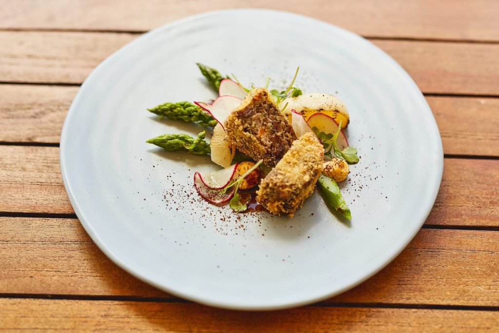 Knuspriges Kroketten-Gericht mit grünem Spargel und Kräutern auf Holztisch – Fine Dining im Weinforum Franken