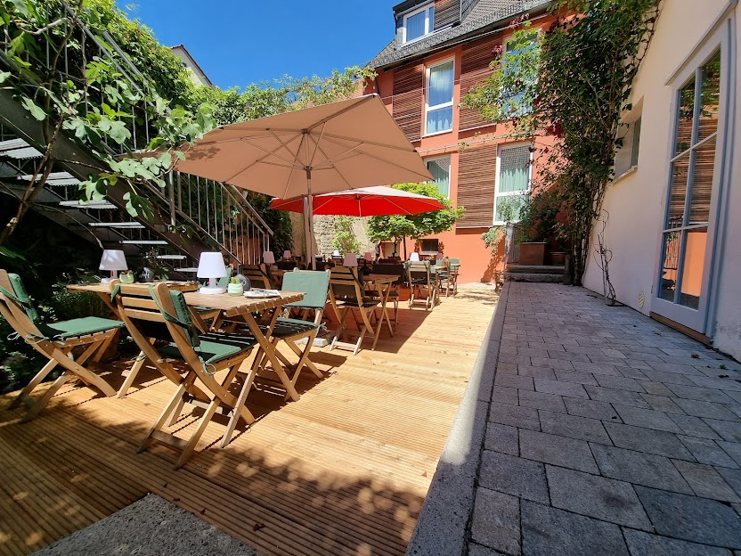 Mediterran begrünter Innenhof des Restaurant Weinforum Franken – Terrasse mit Holzdecking für Sommer-Dining