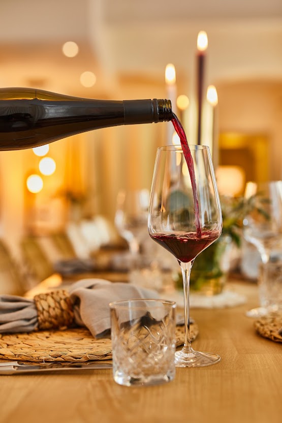 Fränkischer Rotwein wird in ein Kristallglas am festlich gedeckten Tisch im Restaurant Weinforum Franken eingeschenkt